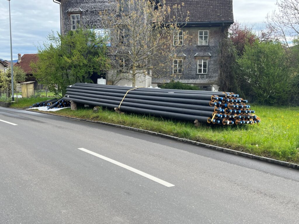 gelagerte Fernwärmerohre am Strassenrand Seestrasse Nuolen vor altem Steinhaus