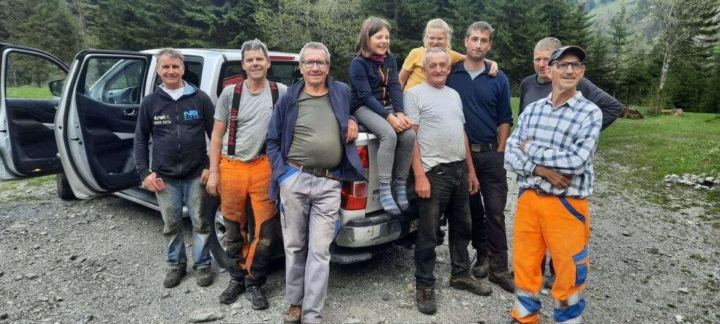 Helfergruppe beim Aufräumen Brüschalp vor Pickup, teils in orangen Forsthosen