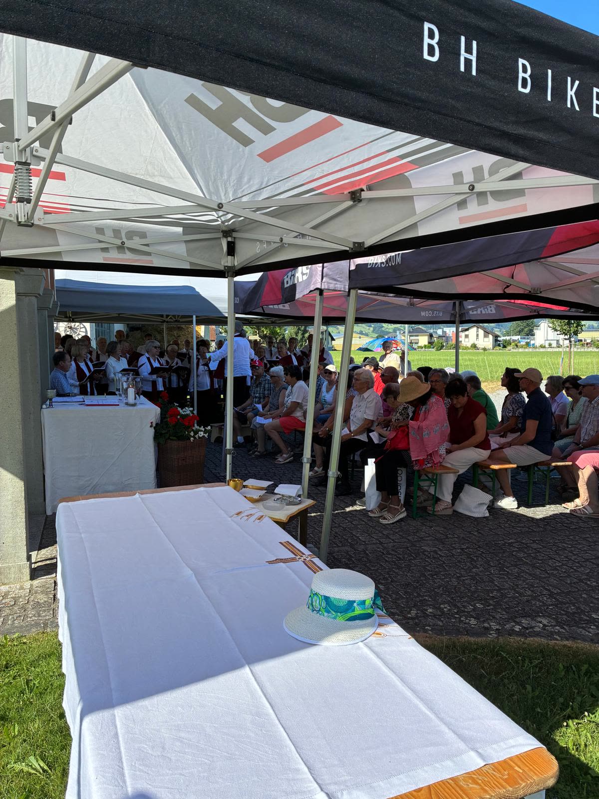 Feldaltar (weisser Tisch) unter Zelt, Besucher im Hintergrund