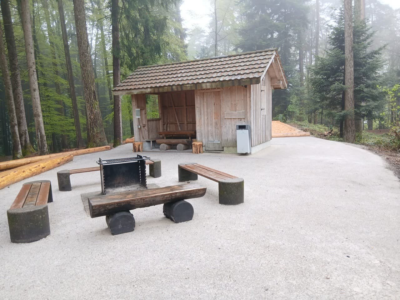 Feuerstelle Buechberg mit Holzbänken, Grillrost und Unterstandshütte im Nebelwald