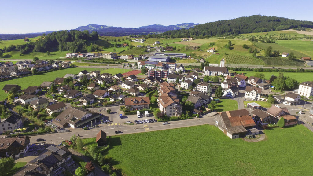 Luftbild der Überbauung Sonnenwiese in Wangen mit mehrgeschossigen Wohnbauten, rechts die Kirche