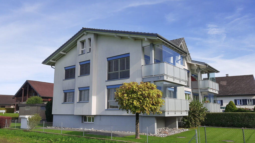 Weisses Mehrfamilienhaus an der Zürcherstrasse 78 mit blau eingefassten Fenstern und verglasten Balkonen